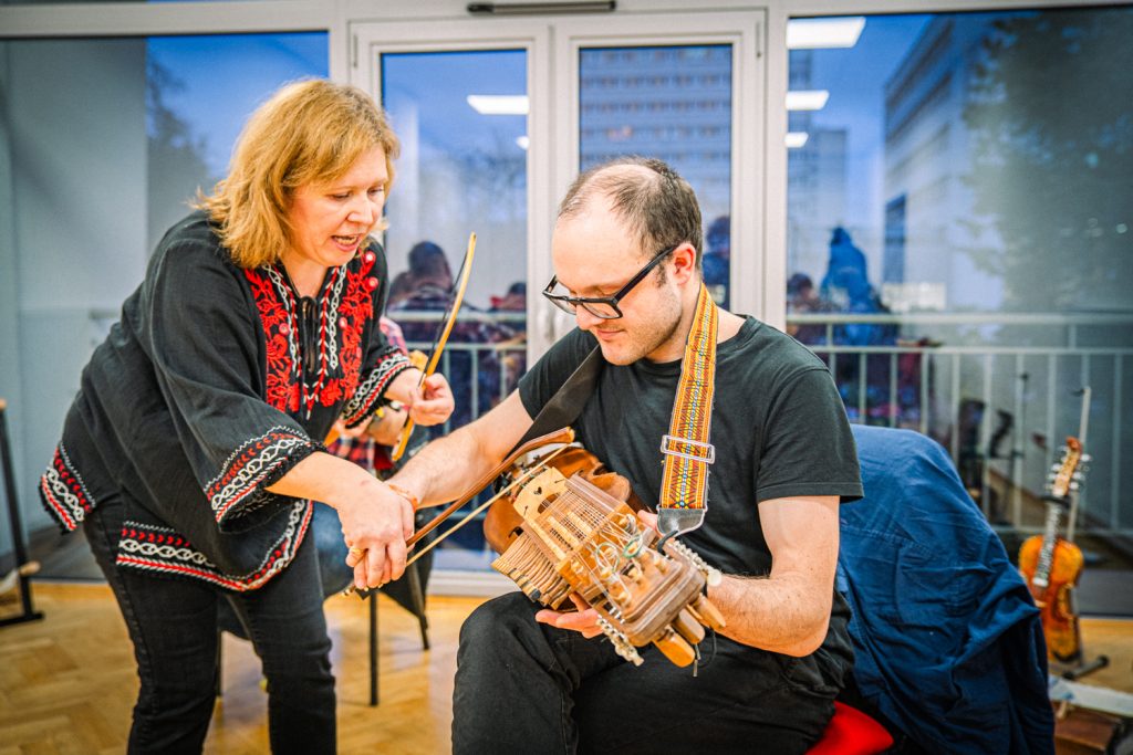 Anna Kołodziej udziela instrukcji prawidłowego prowadzenia smyczka na nyckelharpie podczas warsztatów w Lublinie 2025